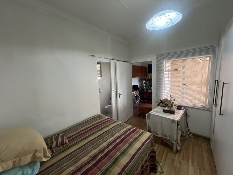A functional bedroom featuring laminate flooring, built-in cupboards, and direct access to an en-suite bathroom.