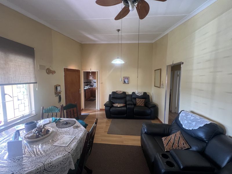 Open plan living and dining area featuring laminate flooring, ceiling fan, and direct access to the kitchen.