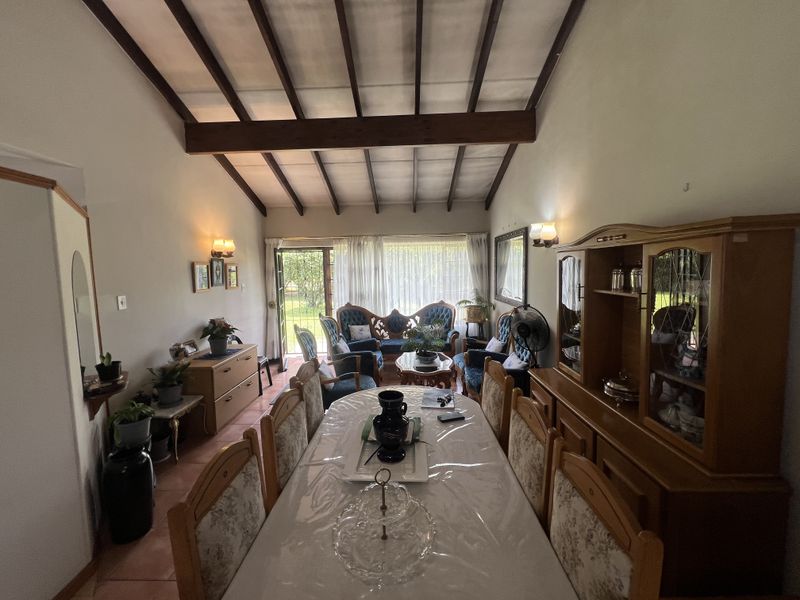 Open plan living and dining area featuring high vaulted ceilings with exposed timber beams and direct access to the rear garden.
