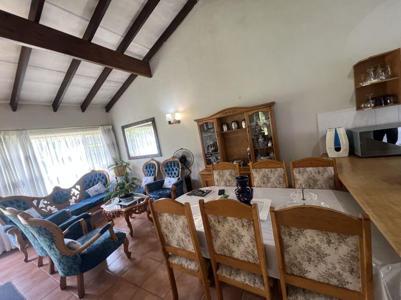 Open plan living and dining area featuring high vaulted ceilings with exposed timber beams and terracotta floor tiles.