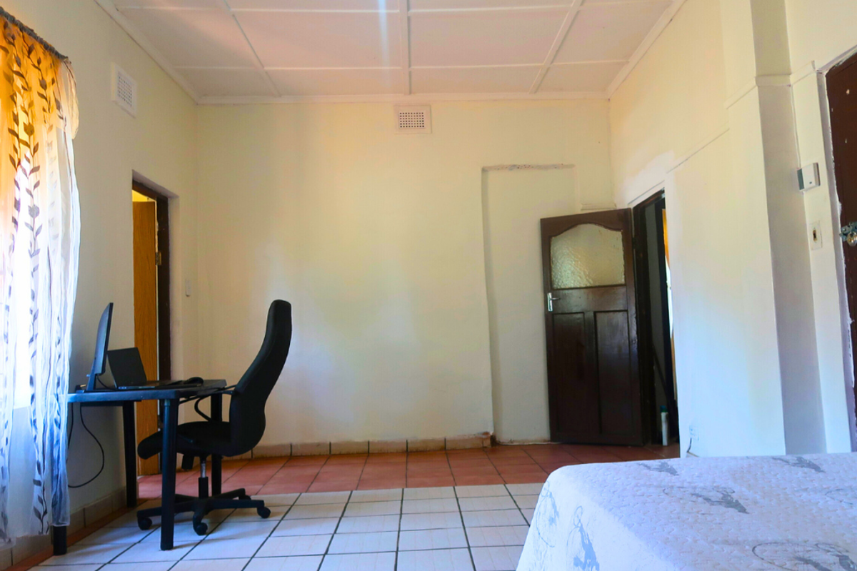 A bedroom featuring tiled flooring, a ceiling with paneling, and multiple doorways leading to adjacent areas of the home.