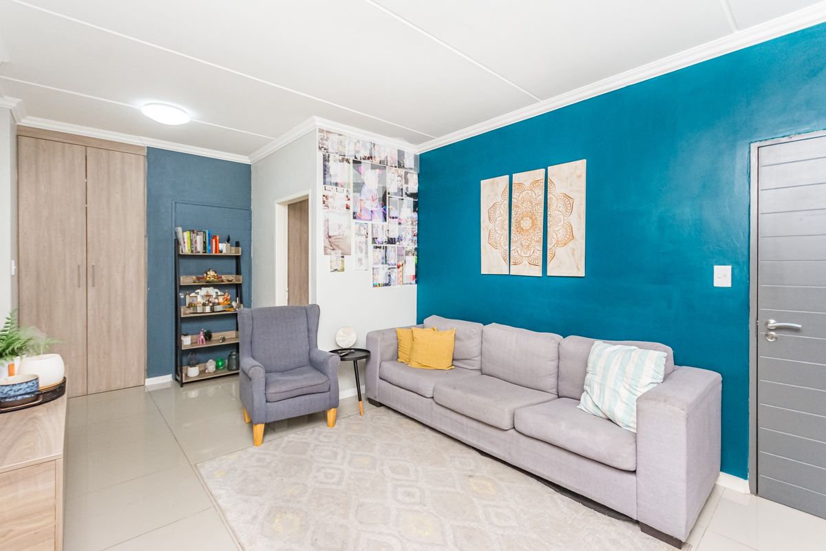 A well-maintained living room featuring tiled flooring, a built-in cupboard, and a bold blue accent wall.