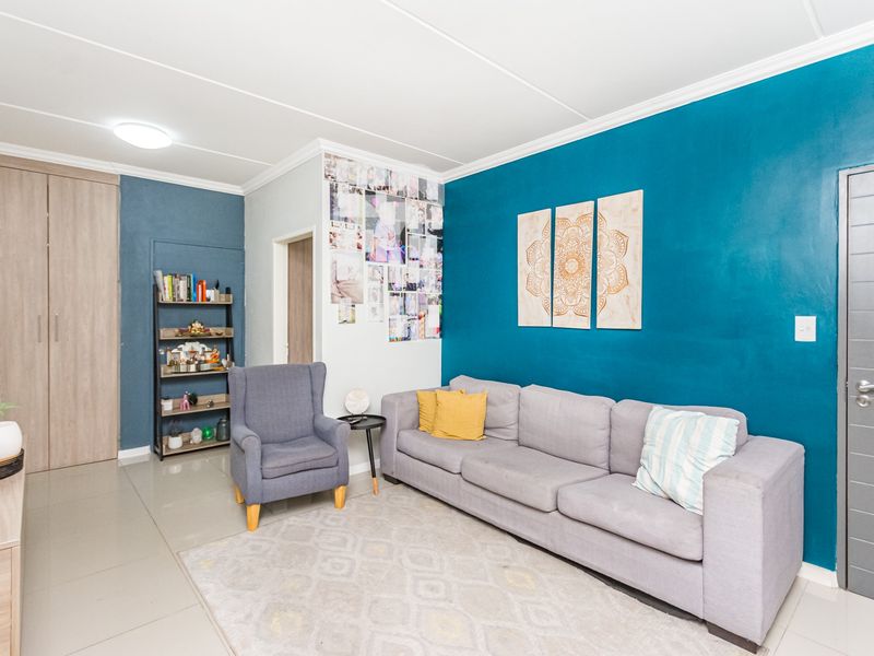 A well-maintained living room featuring tiled flooring, a built-in cupboard, and a bold blue accent wall.