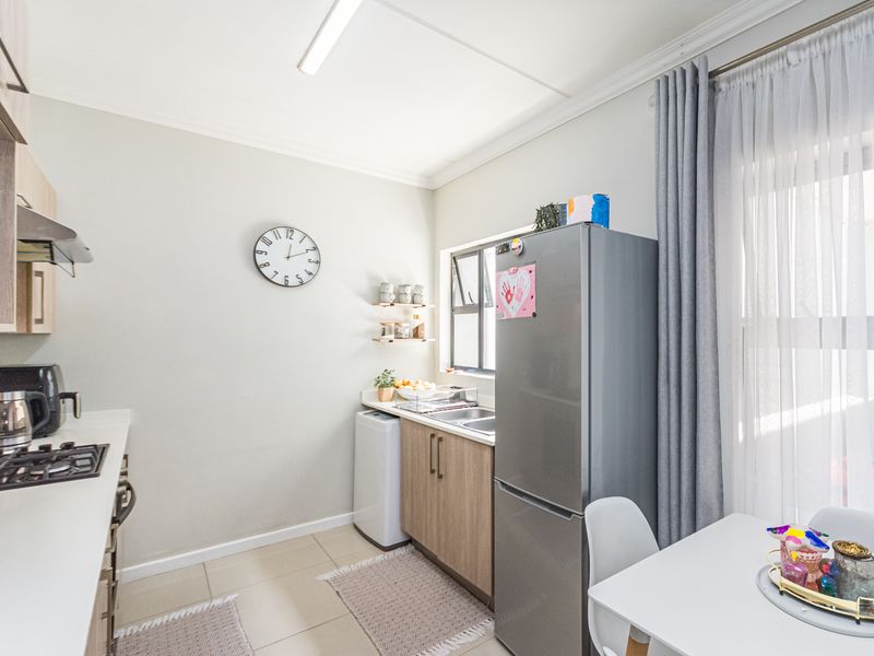 A functional kitchen featuring built-in cabinetry, a gas hob with extractor fan, and tiled flooring, offering a clean and practical workspace.