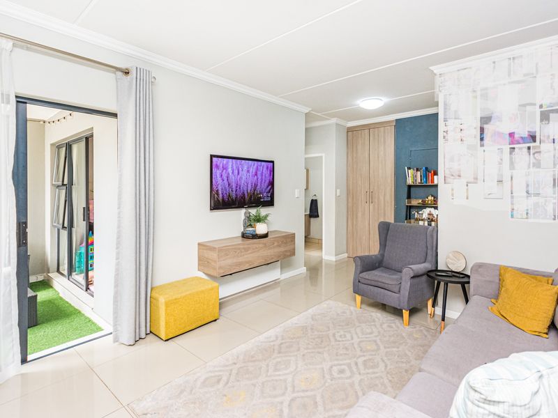 A bright living room featuring tiled flooring, built-in cabinetry, and a sliding glass door providing access to an outdoor balcony area.