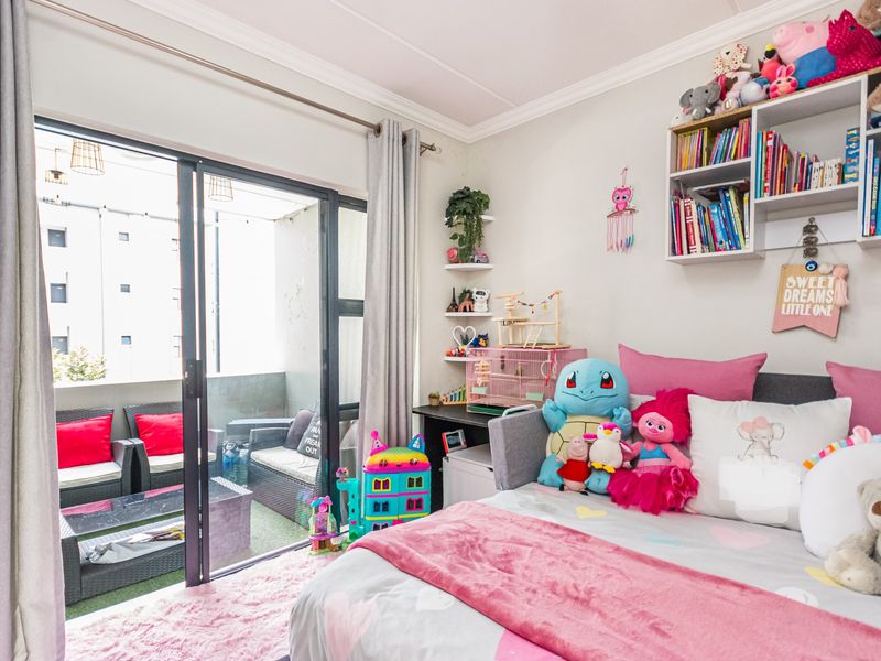 A bright bedroom featuring crown molding, built-in wall shelving, and a large sliding glass door providing direct access to a private balcony.