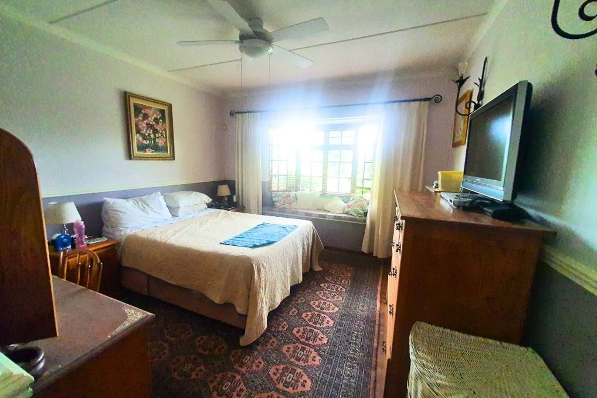 A cozy bedroom featuring a built-in window seat, ceiling fan, and classic window treatments, offering a comfortable and functional living space.