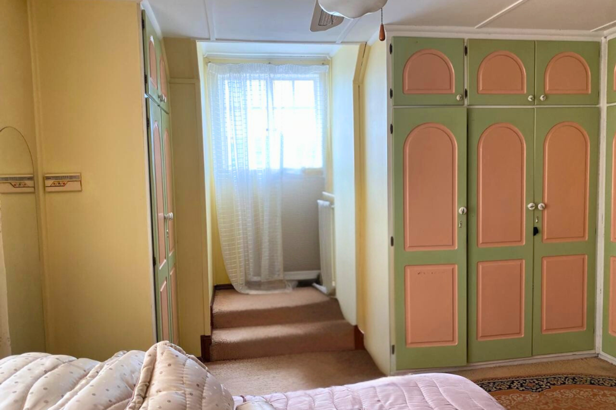A bedroom featuring built-in cabinetry with a vintage aesthetic, carpeted flooring, and a small step-up area leading to a window.