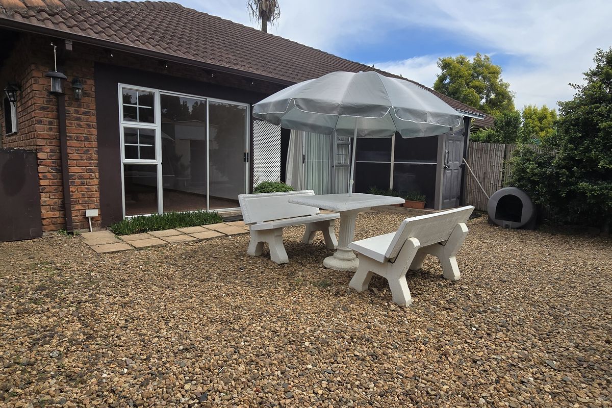 Rear view of the house featuring a brick exterior, sliding glass door access, and a gravel-covered backyard area.
