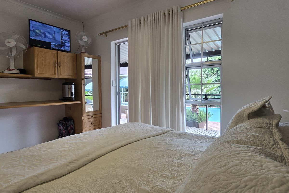 Bedroom featuring built-in shelving and cabinetry, with direct access to an outdoor patio and pool area through a sliding door.