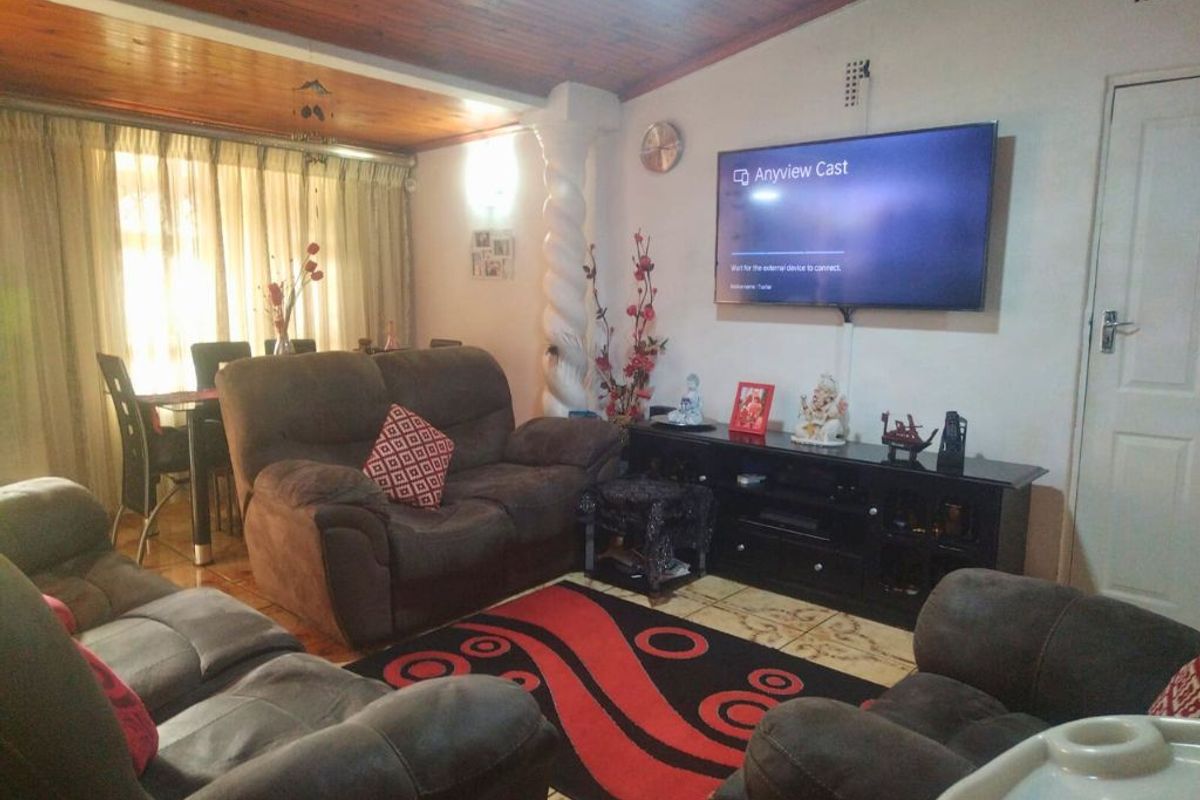 A living room featuring a timber-paneled ceiling, decorative column, and tiled flooring, providing a functional and comfortable space for relaxation.