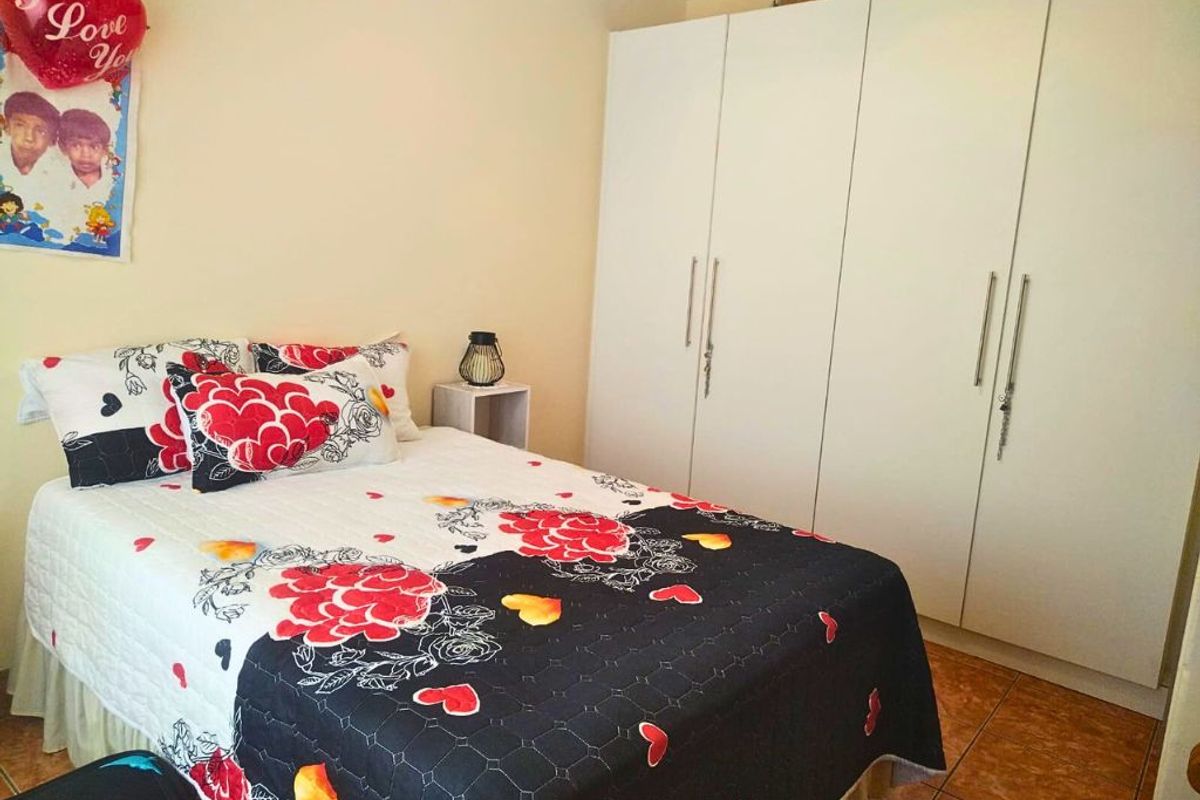 A bedroom featuring built-in white wardrobes and tiled flooring.