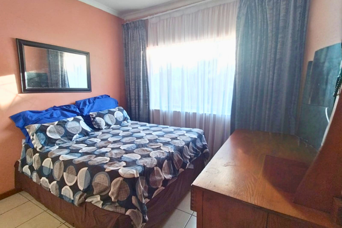 A bedroom featuring tiled flooring and a large window with curtain tracks.
