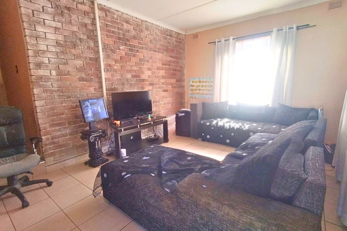 Living room featuring a prominent exposed brick feature wall and tiled flooring, providing a textured focal point for the living space.
