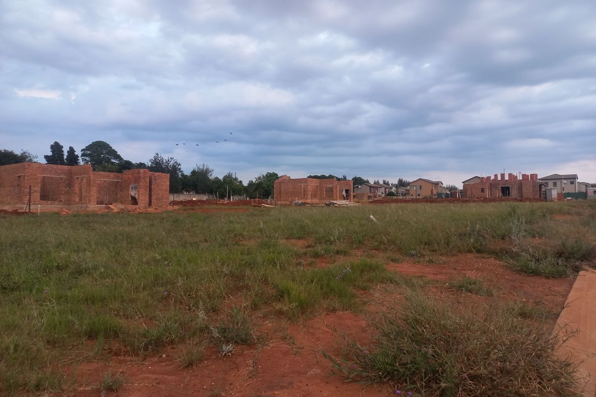 A view of a residential development site featuring multiple brick structures in the early stages of construction on a large plot of land.