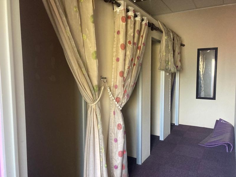 A utility area featuring partitioned changing cubicles with curtain enclosures, carpeted flooring, and a drop ceiling.