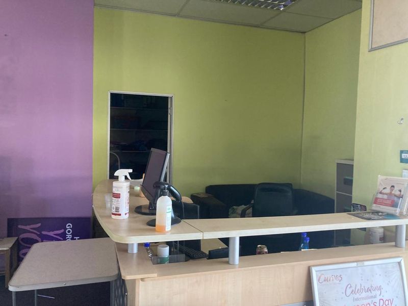 A retail reception area featuring a built-in service counter, suspended ceiling, and painted walls in need of cosmetic refreshment.