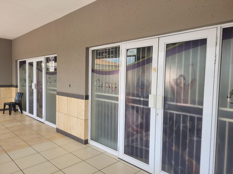 Front entrance view of a retail unit featuring tiled flooring, aluminium framed glass doors, and decorative wall tiling.