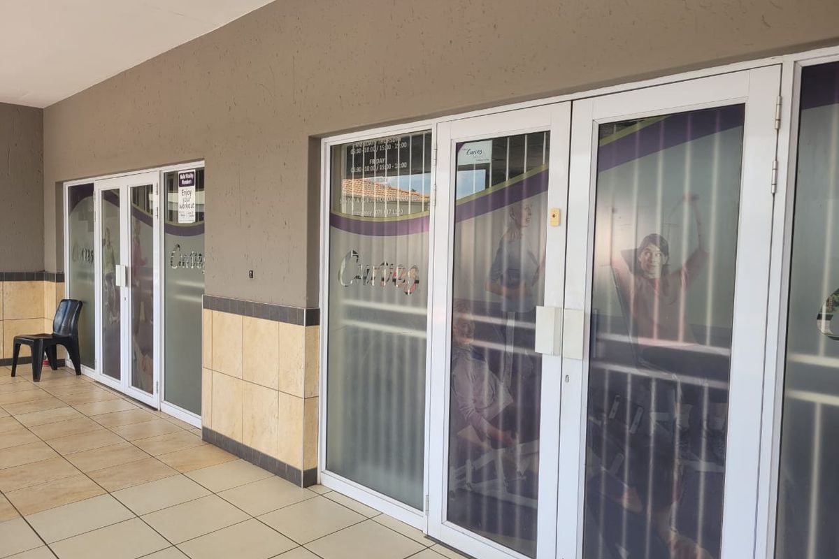Front entrance view of a retail unit featuring tiled flooring, aluminium framed glass doors, and decorative wall tiling.