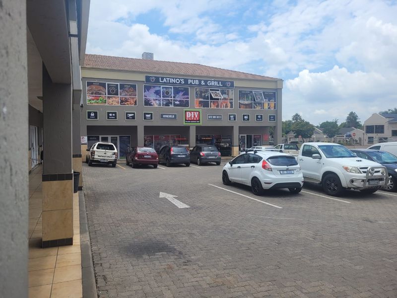 Front view of a commercial retail property featuring a paved parking area, covered walkway, and prominent signage for a pub and grill.