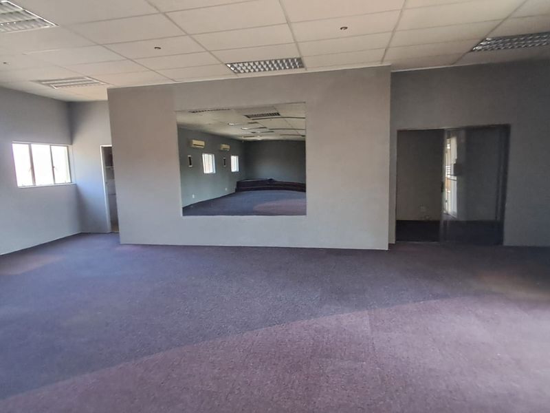 Spacious open-plan retail area featuring a suspended ceiling, recessed lighting, wall-mounted air conditioning, and a large feature mirror.