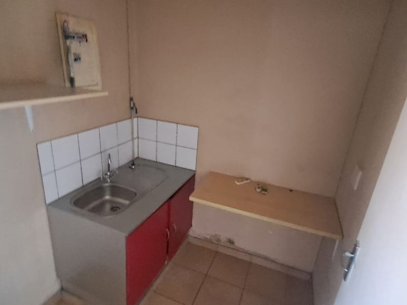 A compact utility or scullery area featuring a stainless steel sink, tiled splashback, and built-in cabinetry, suitable for a small prep or wash-up space.