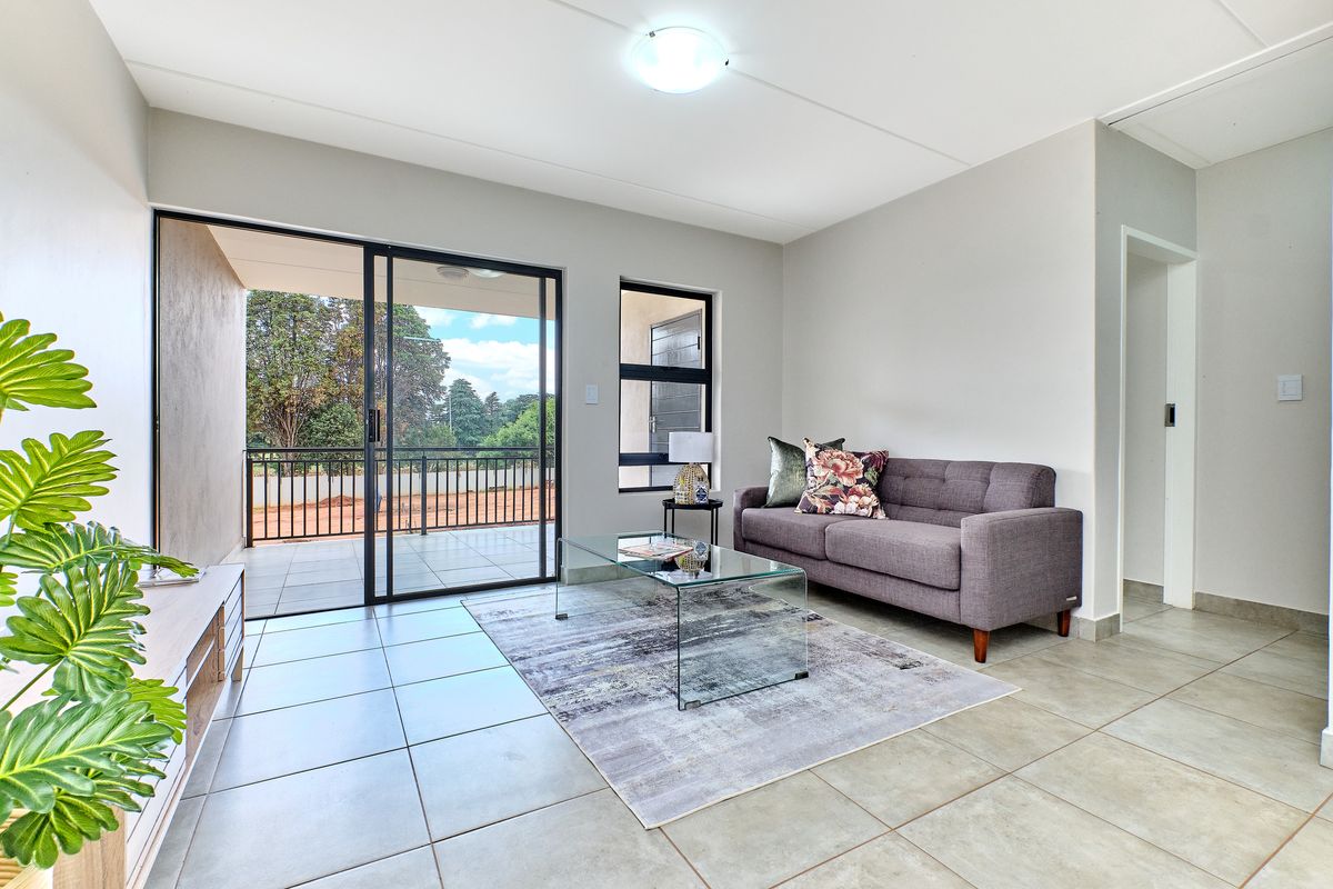 Bright living room featuring large sliding glass doors leading to a private balcony, tiled flooring, and neutral wall finishes.