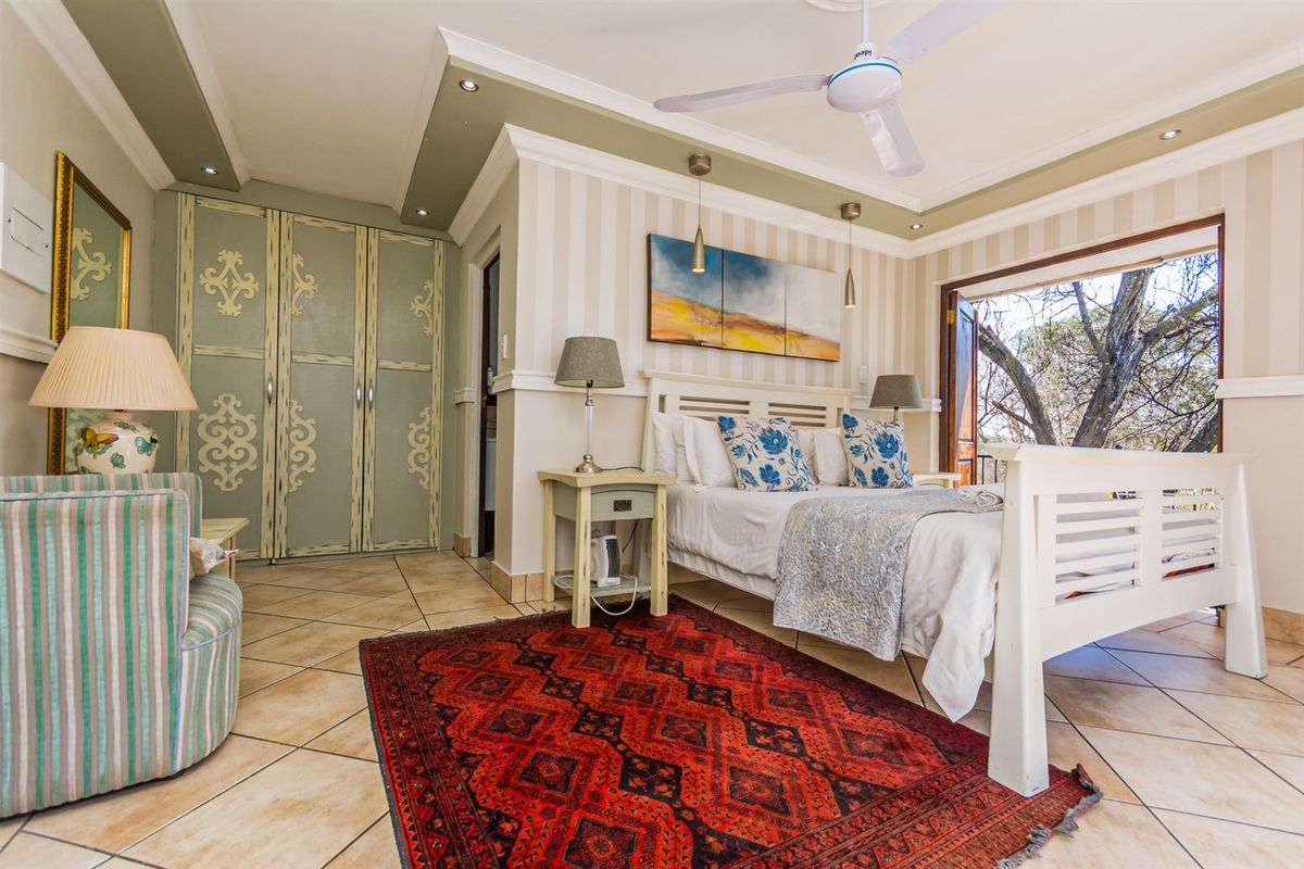 A well-appointed bedroom featuring tiled flooring, built-in cabinetry, a ceiling fan, and direct access to an outdoor area through large doors.