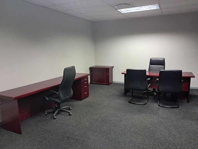 A functional office space featuring neutral walls, carpeted flooring, and recessed ceiling lighting, providing a professional environment for work.