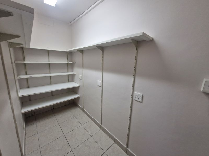 A clean, functional utility or storage room featuring wall-mounted shelving units, tiled flooring, and integrated electrical points.