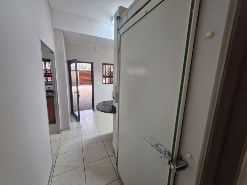 A functional hallway area featuring tiled flooring, a built-in counter, and direct access to an outdoor paved space.