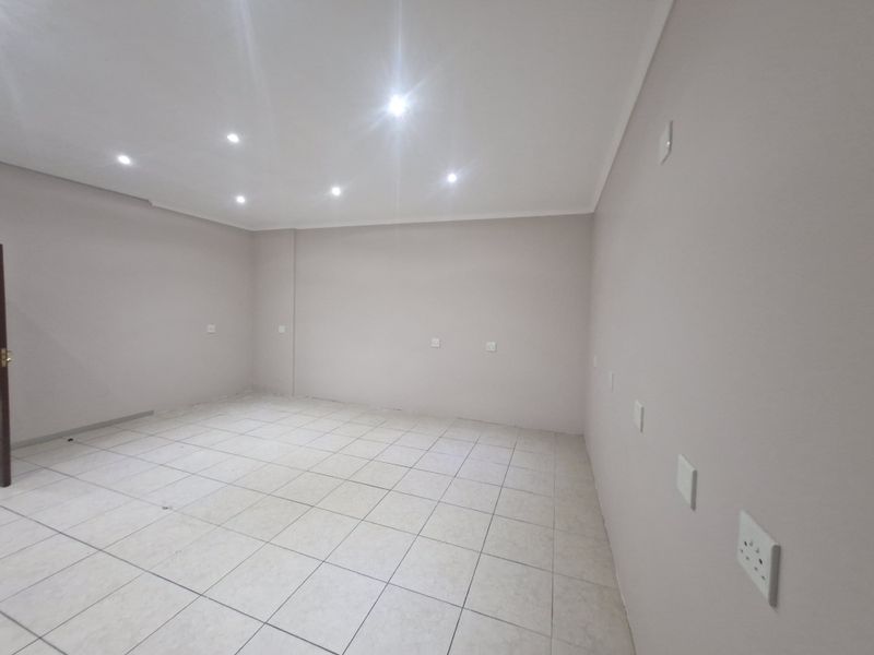 A clean, vacant office space featuring neutral wall finishes, tiled flooring, and recessed ceiling lighting with multiple integrated power and data points.