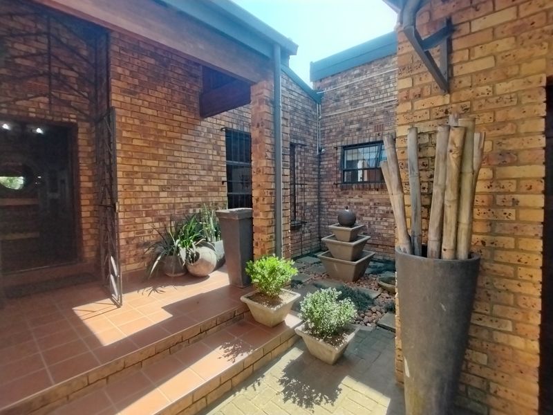 A charming, covered brick patio area featuring a tiered water feature and tiled flooring, offering a peaceful outdoor space.