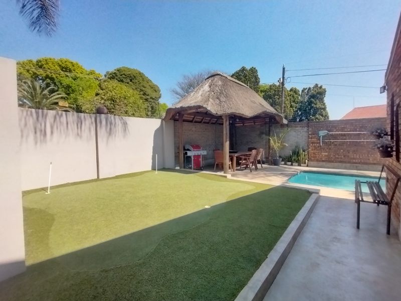 Outdoor entertainment area featuring a swimming pool, a thatched lapa, and a private artificial grass putting green.