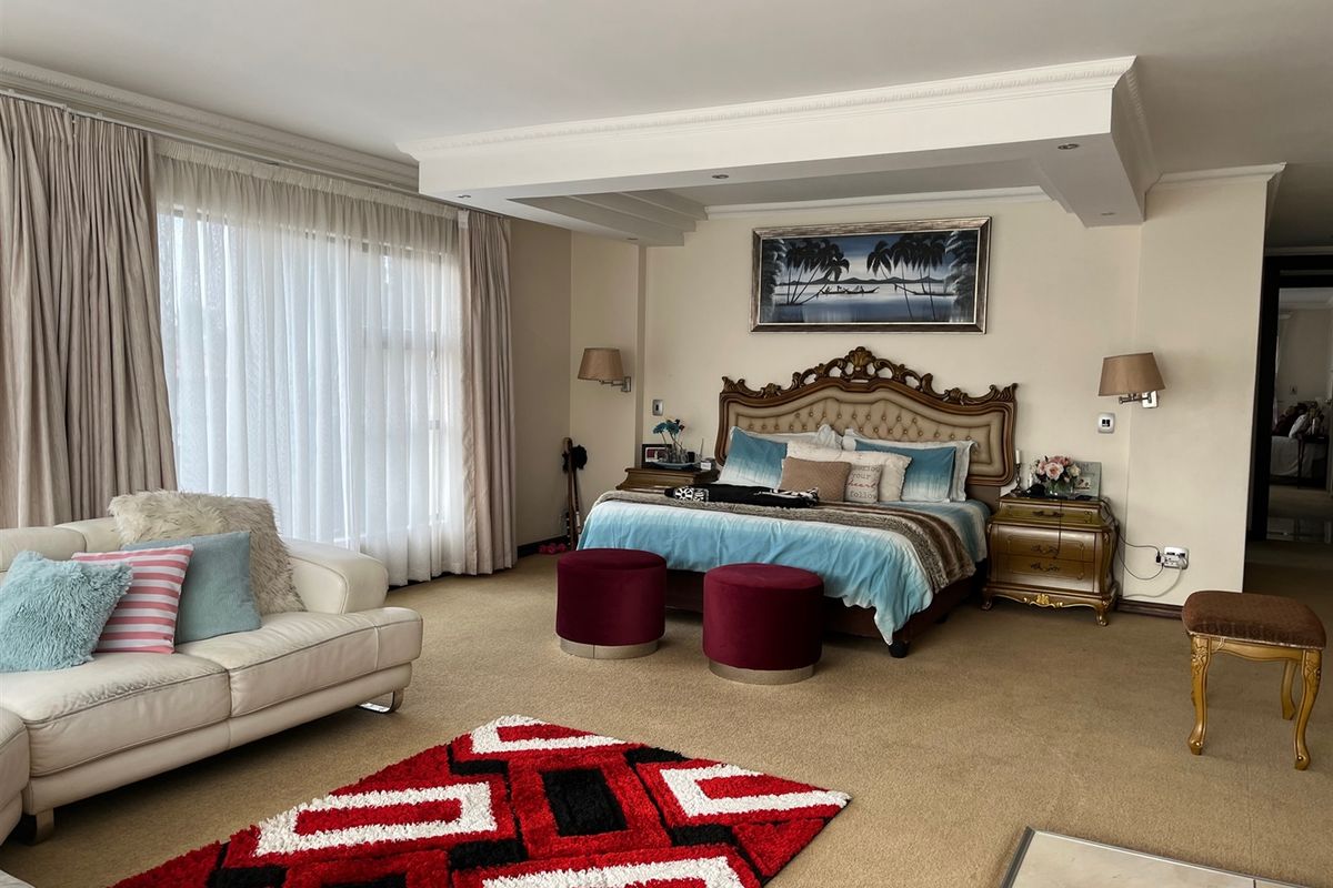 Spacious bedroom featuring a recessed ceiling with coving, wall-mounted lighting, and large windows allowing for ample natural light.