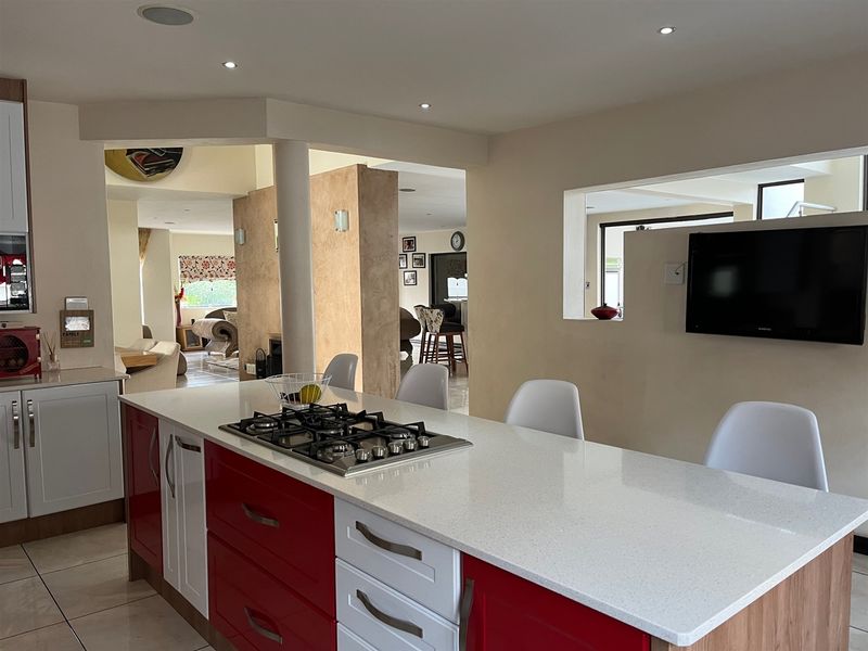 Spacious open-plan kitchen featuring a central island with a gas cooktop, stone countertops, and integrated cabinetry, flowing into the adjacent living areas.