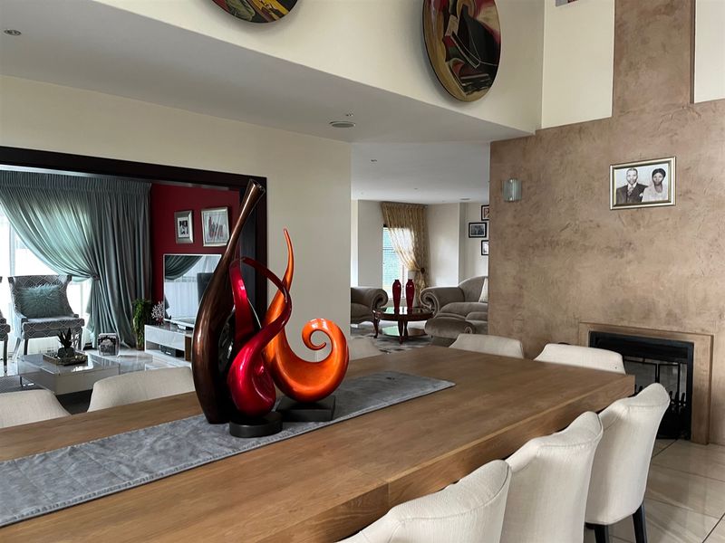 Spacious open-plan living and dining area featuring a prominent fireplace, recessed lighting, and neutral tiled flooring throughout the connected living spaces.