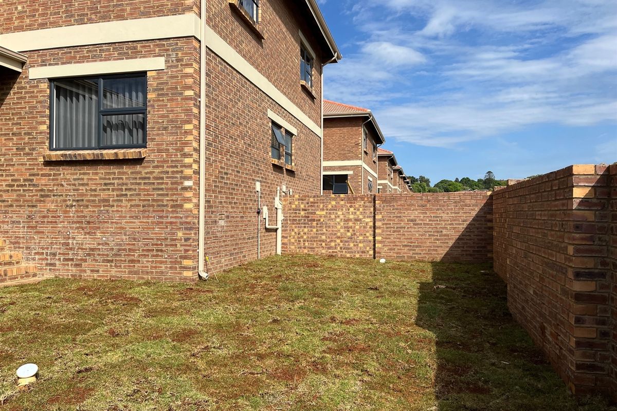 A private rear garden area featuring face-brick boundary walls and a view of the townhouse exterior facade.