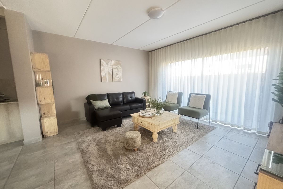 A bright and spacious living room featuring neutral tiled flooring and a large sliding glass door that allows for ample natural light.