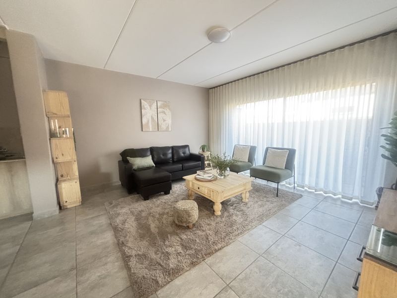 A bright and spacious living room featuring neutral tiled flooring and a large sliding glass door that allows for ample natural light.