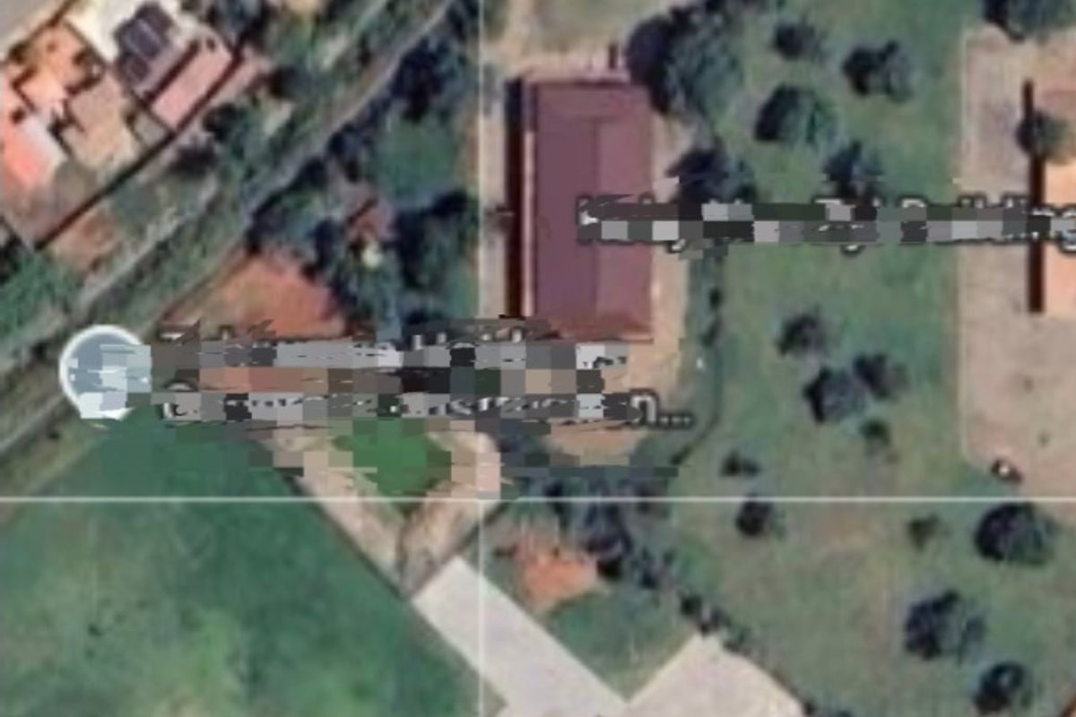 An aerial view of the industrial property site showing the building footprint, surrounding grounds, and access driveway.