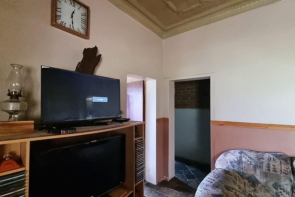 Living room featuring an ornate ceiling and timber dado rail, showing signs of wear and requiring cosmetic updates.