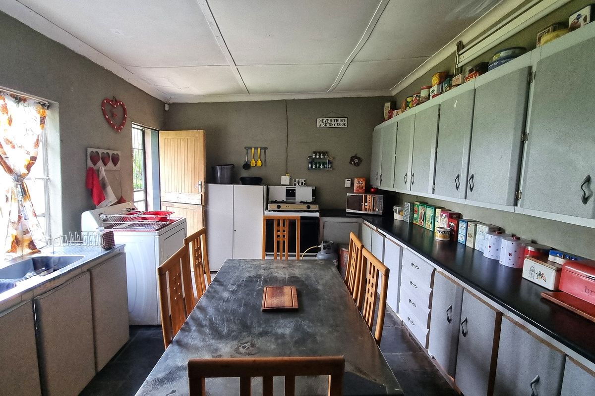 A functional kitchen featuring extensive built-in cabinetry, laminate countertops, and a stainless steel sink, offering a practical layout with potential for modern updates.