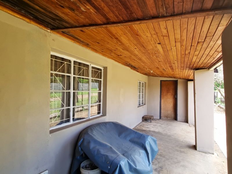A covered outdoor patio area featuring a timber-clad ceiling, concrete flooring, and security-barred windows, providing a functional transition space to the exterior.