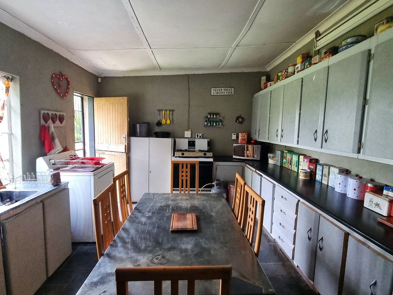 A functional kitchen featuring extensive built-in cabinetry, laminate countertops, and a stainless steel sink, offering a practical layout with potential for modern updates.