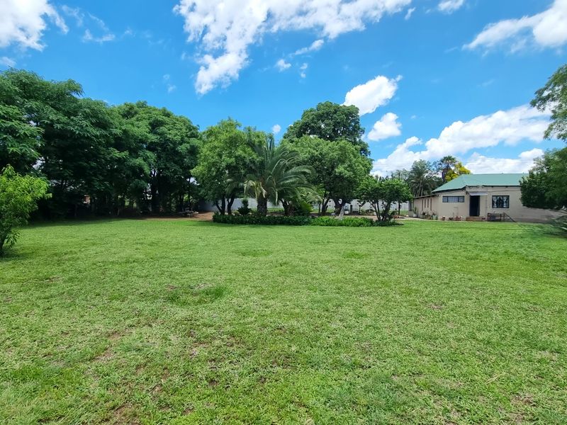 A spacious, well-maintained green lawn surrounded by mature trees and established landscaping, providing a peaceful outdoor setting.