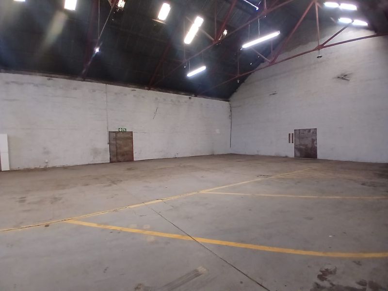 A large, open-plan industrial utility space featuring high ceilings with exposed steel trusses, concrete flooring, and functional overhead lighting.