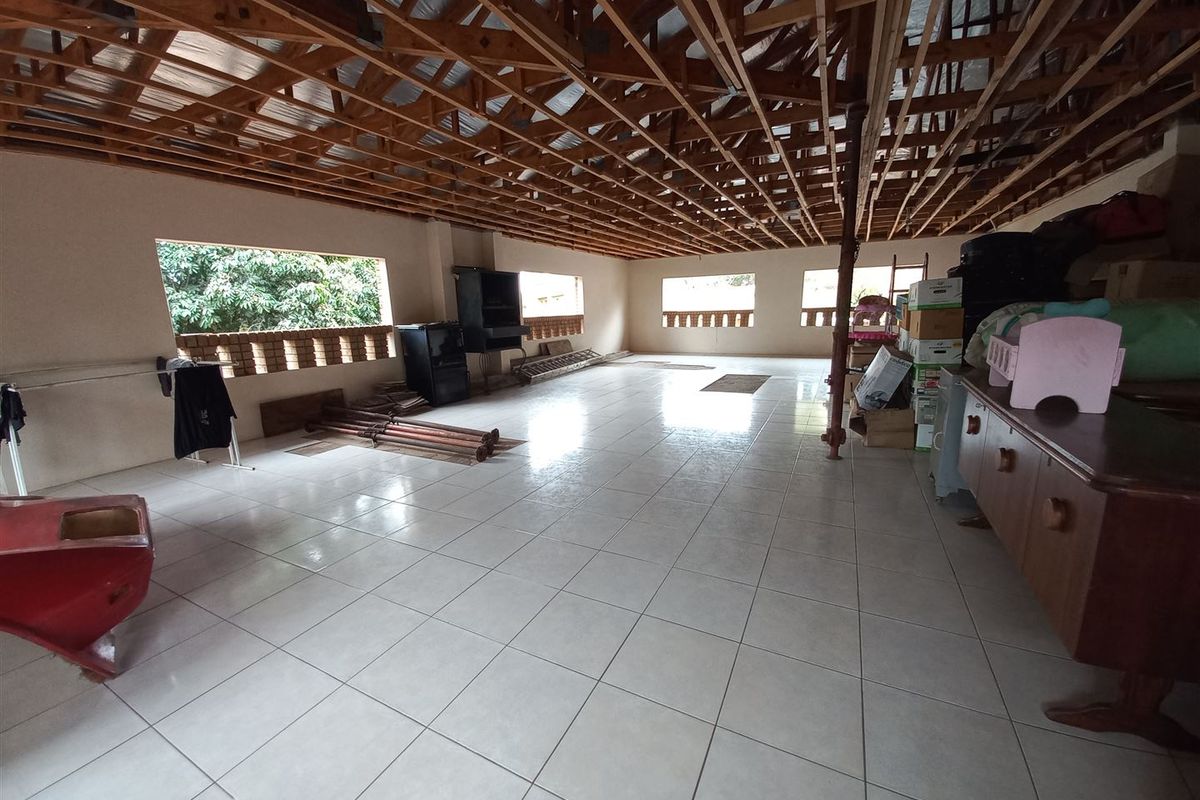 Large open-plan living area featuring ceramic floor tiles and exposed timber roof trusses, currently in an unfinished state awaiting completion.