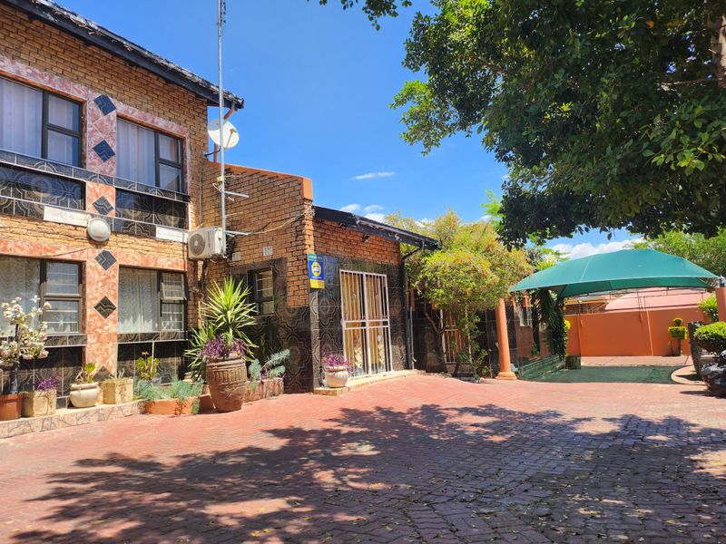 Front exterior view of a brick-faced house featuring a paved driveway, security gate, and an installed shade sail area.