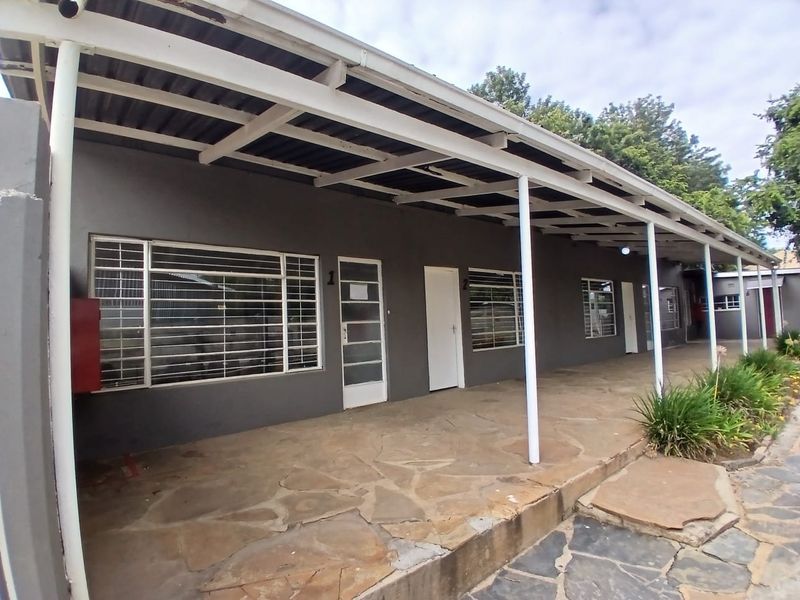 A covered outdoor patio area featuring flagstone flooring, steel support columns, and multiple access points with security bars.